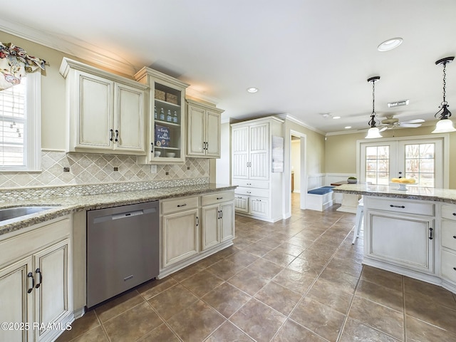 kitchen with hanging light fixtures, a wealth of natural light, cream cabinets, and dishwasher