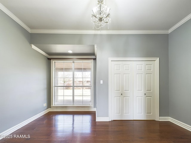 unfurnished bedroom with crown molding, dark wood-type flooring, a closet, and a chandelier