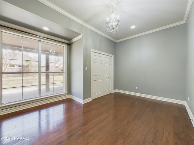 spare room featuring ornamental molding, dark wood-type flooring, and a notable chandelier