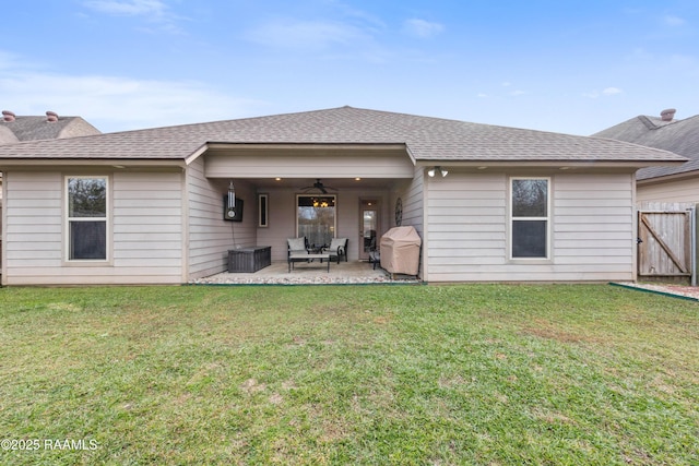 rear view of house with ceiling fan, a lawn, and a patio area