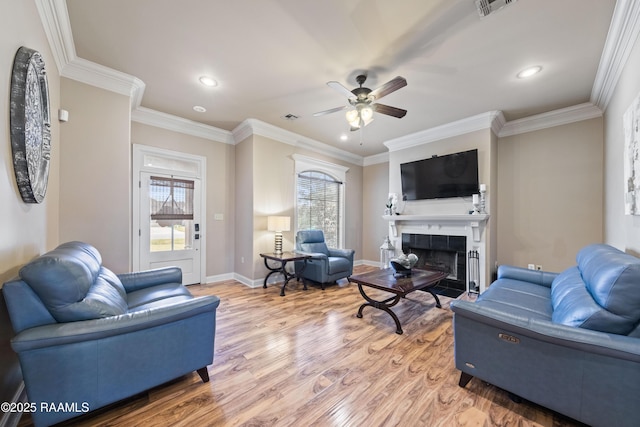 living room featuring a tiled fireplace, ceiling fan, ornamental molding, and wood-type flooring