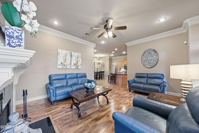 living room with ceiling fan with notable chandelier, sink, light wood-type flooring, and crown molding