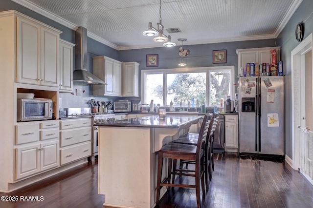 kitchen featuring a center island, wall chimney range hood, dark hardwood / wood-style flooring, pendant lighting, and appliances with stainless steel finishes