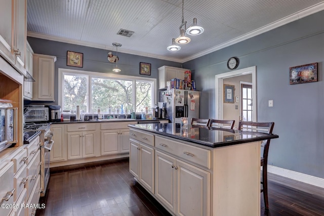 kitchen featuring decorative light fixtures, a kitchen island, a breakfast bar, and appliances with stainless steel finishes