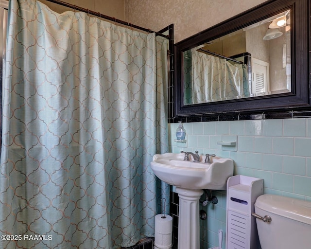 bathroom featuring toilet, walk in shower, and tile walls