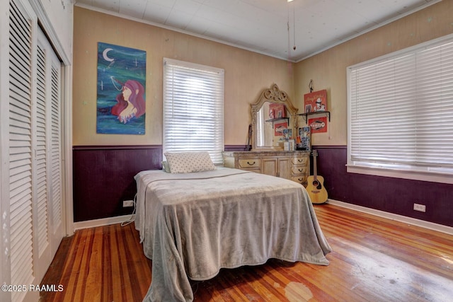 bedroom with crown molding, wood walls, and hardwood / wood-style flooring