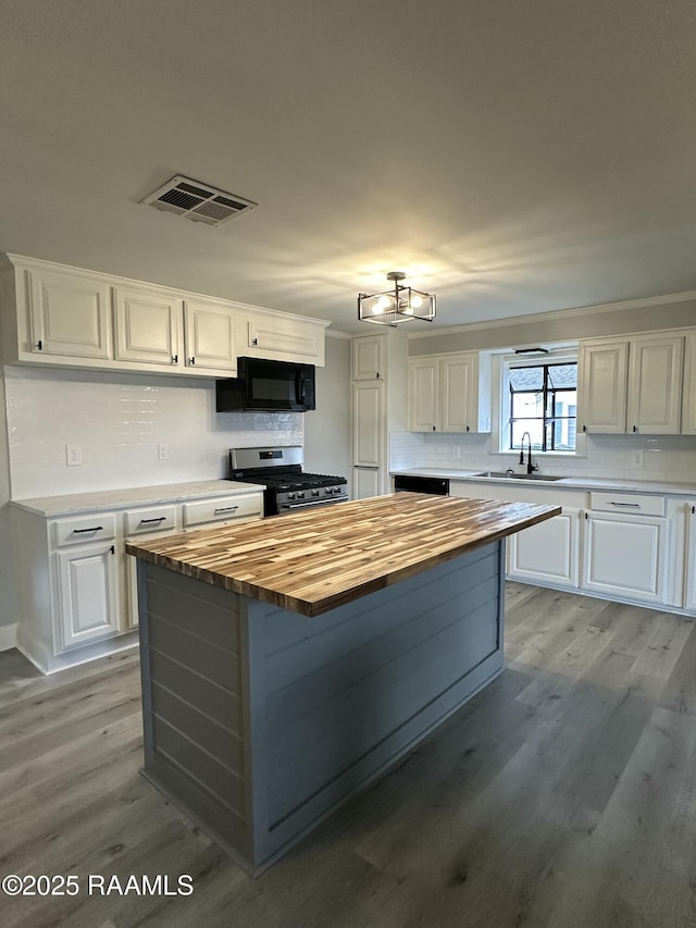 kitchen featuring wood counters, white cabinetry, sink, and gas range