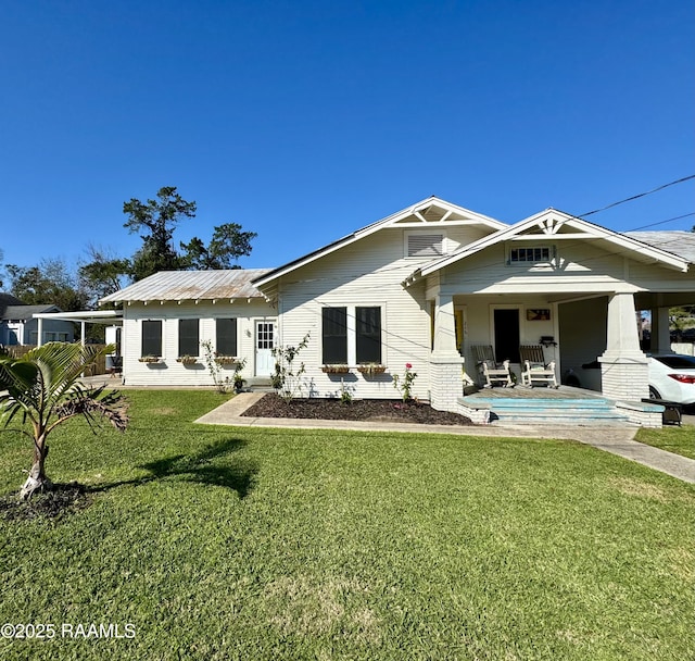 rear view of property featuring a yard and covered porch