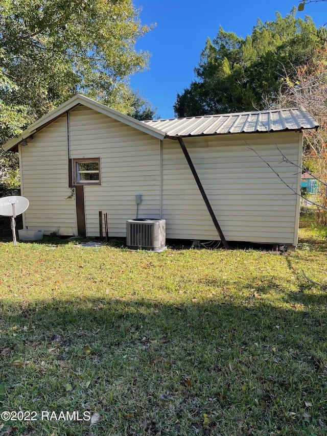 view of side of home with central AC unit and a yard