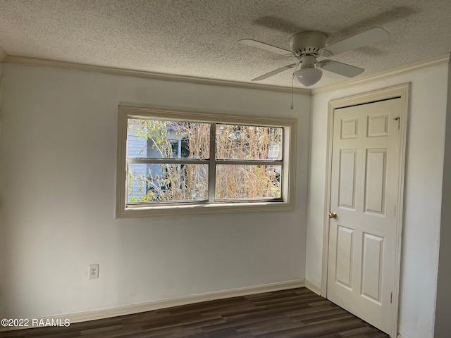 empty room with a textured ceiling, dark hardwood / wood-style flooring, plenty of natural light, and ceiling fan