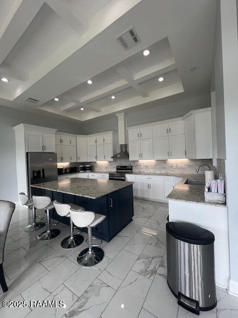 kitchen featuring white cabinetry, appliances with stainless steel finishes, a large island, and a breakfast bar area