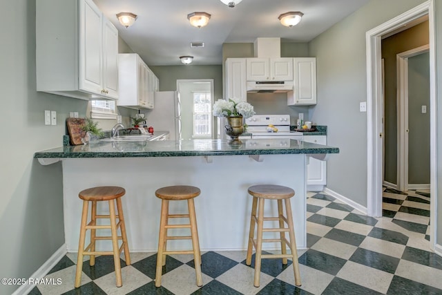 kitchen with white appliances, white cabinetry, a breakfast bar area, and sink