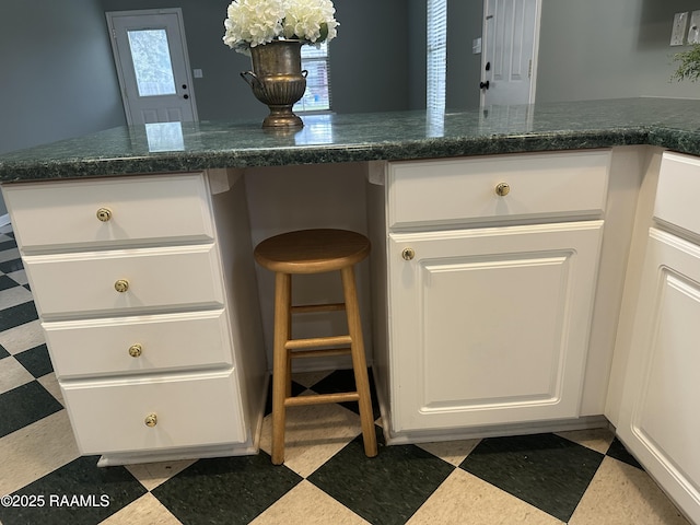 kitchen with a wealth of natural light, white cabinetry, and built in desk