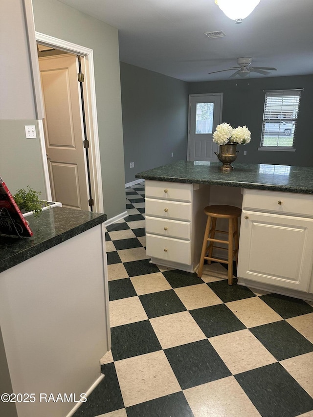 kitchen featuring white cabinets, ceiling fan, built in desk, and kitchen peninsula