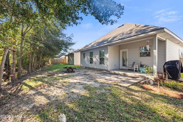 rear view of property featuring a fire pit and a patio area