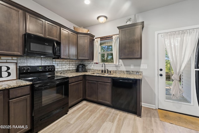 kitchen featuring black appliances, light wood-type flooring, light stone countertops, dark brown cabinetry, and sink