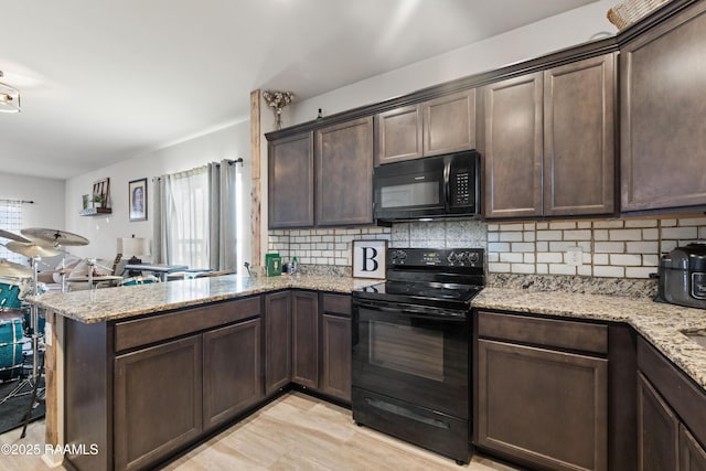 kitchen featuring kitchen peninsula, light stone countertops, black appliances, and dark brown cabinetry