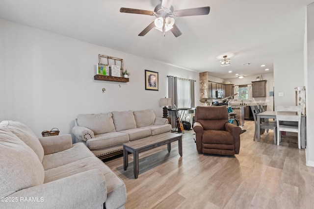 living room with ceiling fan and light hardwood / wood-style flooring