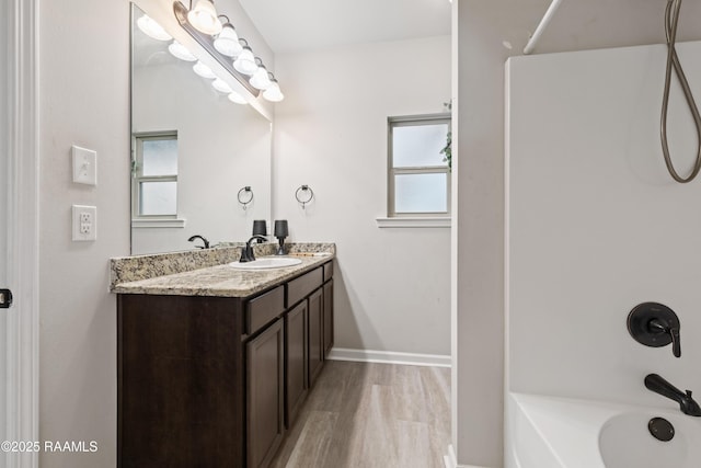 bathroom featuring bathing tub / shower combination, a healthy amount of sunlight, hardwood / wood-style floors, and vanity