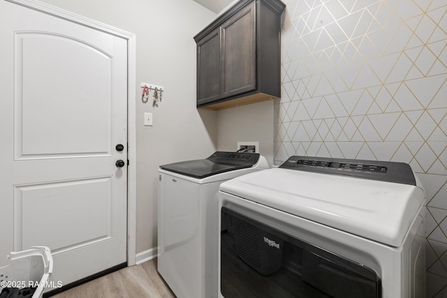 washroom with light hardwood / wood-style flooring, cabinets, and washer and clothes dryer