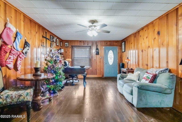 living room with ceiling fan, dark wood-type flooring, and wooden walls