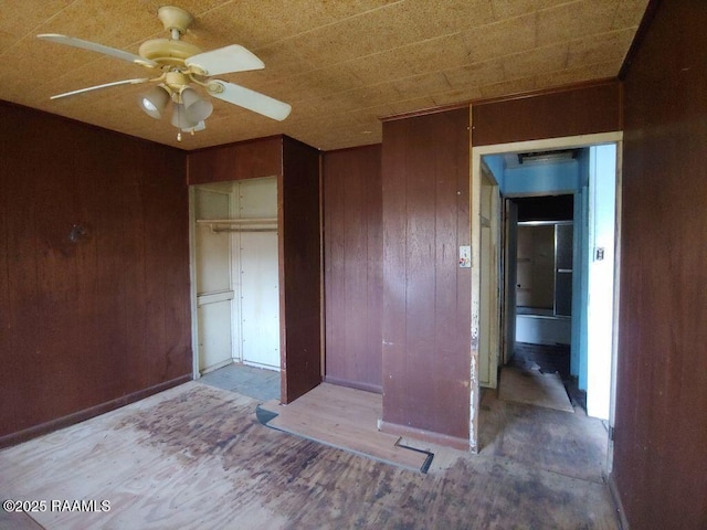 unfurnished bedroom with wood walls, a closet, and ceiling fan