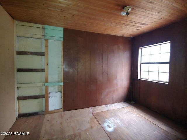 unfurnished room featuring wood ceiling and wooden walls