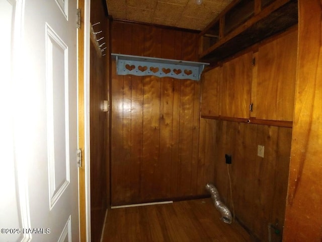 laundry area featuring wooden walls, cabinets, and wood-type flooring