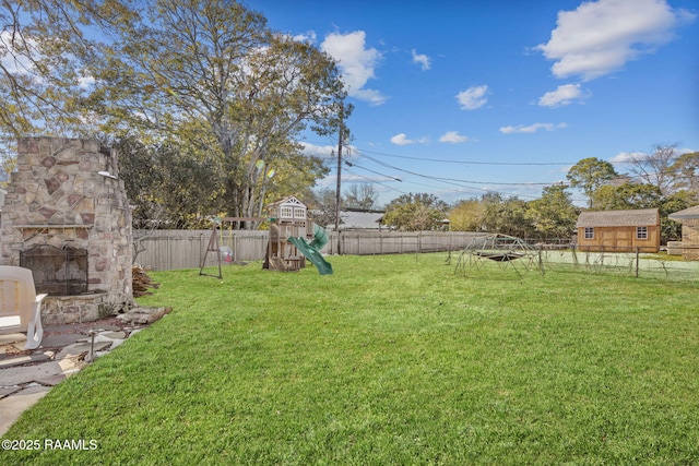 view of yard with a playground and an outdoor stone fireplace