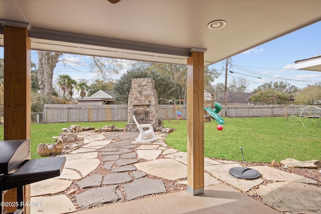 view of patio featuring a playground and an outdoor stone fireplace