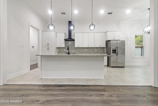 kitchen featuring a kitchen island with sink, stainless steel refrigerator with ice dispenser, light hardwood / wood-style floors, light stone counters, and white cabinetry