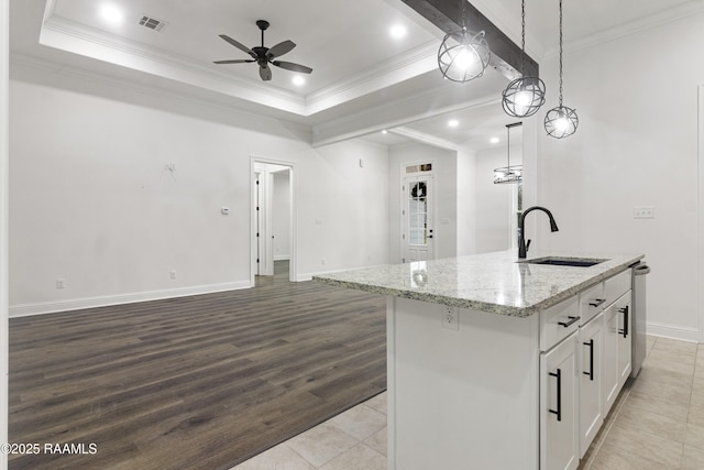 kitchen with light stone countertops, a kitchen island with sink, sink, white cabinets, and hanging light fixtures