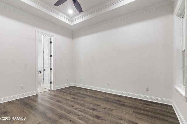 unfurnished room with ceiling fan, dark hardwood / wood-style flooring, ornamental molding, and a tray ceiling