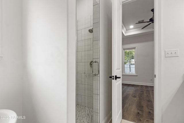 bathroom featuring ceiling fan, a shower with door, wood-type flooring, and ornamental molding