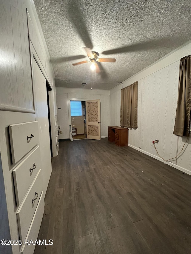 unfurnished bedroom featuring ceiling fan, dark wood-type flooring, and a textured ceiling