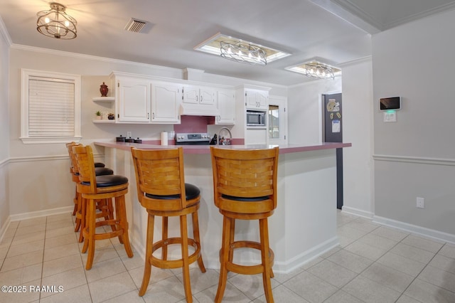 kitchen featuring white cabinetry, a kitchen breakfast bar, stainless steel appliances, ornamental molding, and kitchen peninsula