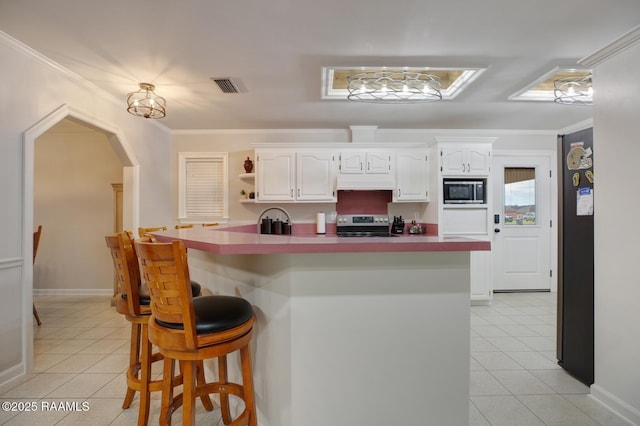 kitchen with built in microwave, a kitchen bar, crown molding, stainless steel electric range, and white cabinets