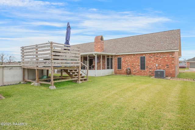 back of property featuring a sunroom, a yard, and central AC