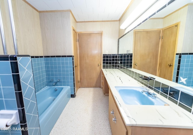 bathroom with a tub, tile walls, ornamental molding, and vanity