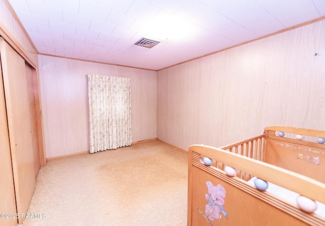 unfurnished bedroom featuring light carpet, a nursery area, a closet, and ornamental molding