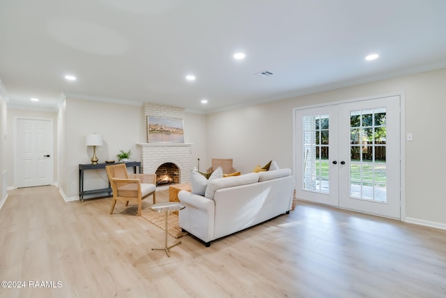 living room with a brick fireplace, light wood-type flooring, french doors, and crown molding