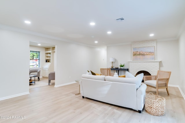 living room with light hardwood / wood-style floors, a brick fireplace, and crown molding