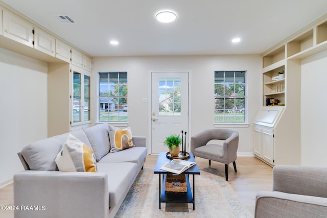 living room featuring light wood-type flooring and built in shelves