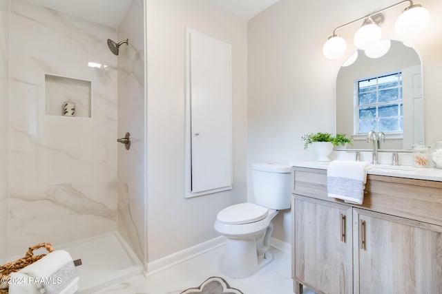 bathroom with toilet, tiled shower, and vanity