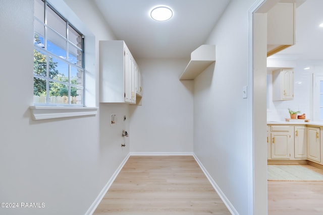 clothes washing area featuring light hardwood / wood-style floors, cabinets, and hookup for a gas dryer