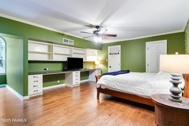 bedroom featuring ornamental molding, built in desk, light hardwood / wood-style floors, and ceiling fan