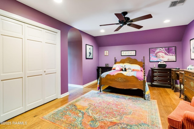 bedroom featuring vaulted ceiling, ceiling fan, light wood-type flooring, and a closet