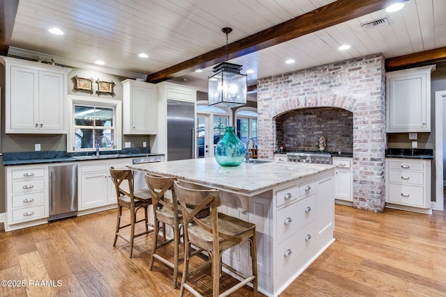 kitchen featuring sink, white cabinetry, decorative light fixtures, a center island, and stainless steel appliances