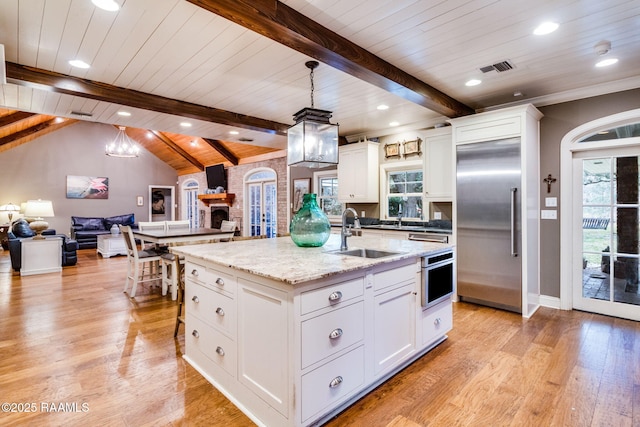 kitchen featuring stainless steel appliances, hanging light fixtures, sink, and a center island with sink