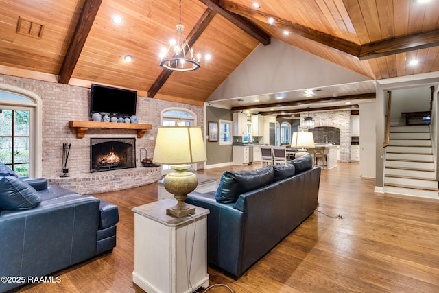 living room with wooden ceiling, high vaulted ceiling, a brick fireplace, and light hardwood / wood-style flooring